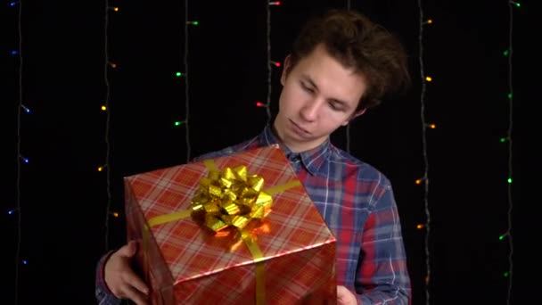Chlapec s dárkovou krabicí na černém pozadí. dárková krabička se stuhou na Šťastný Nový rok, Veselé Vánoce, Valentýn, narozeniny — Stock video