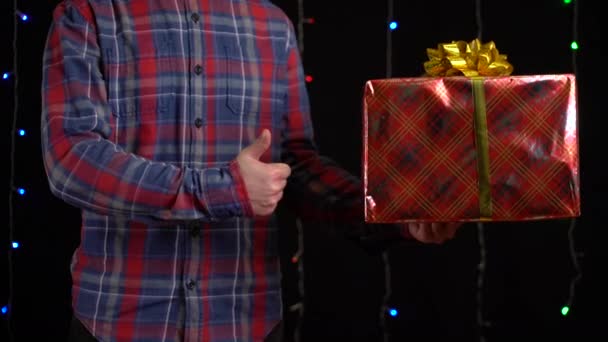 Ragazzo con una scatola regalo su sfondo nero. confezione regalo con nastro per Felice Anno Nuovo, Buon Natale, San Valentino, compleanno — Video Stock