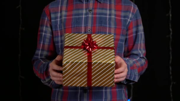 Niño con una caja de regalo sobre fondo negro. caja de regalo con cinta para Feliz Año Nuevo, Feliz Navidad, Día de San Valentín, cumpleaños — Vídeo de stock