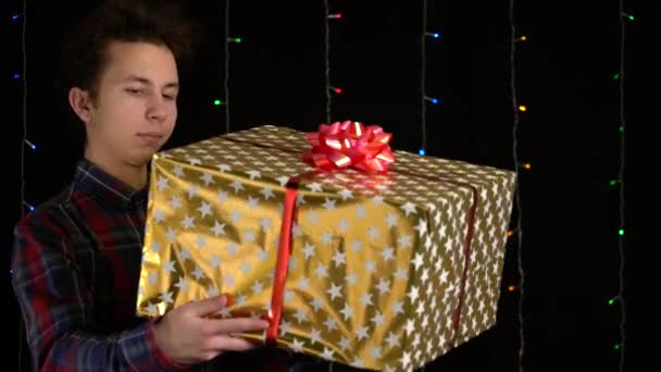 Jongen met een geschenkdoos op zwarte achtergrond. geschenkdoos met lint voor Gelukkig Nieuwjaar, Vrolijk Kerstfeest, Valentijnsdag, verjaardag — Stockvideo