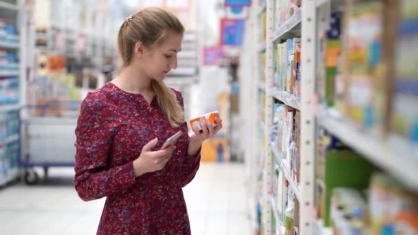 Attraktive junge Frau bei der Auswahl von Produkten im Supermarkt. — Stockvideo