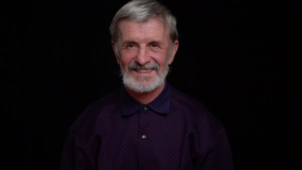 Elderly man, close portrait on a black background. — 비디오
