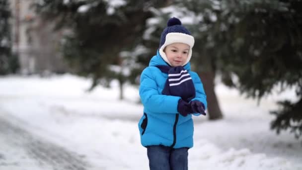 Cute four years old boy in blue winter clothes walks in snowy street — 비디오