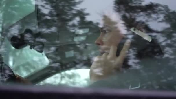 Den unge mannen sitter i bilen och pratar i telefon.. — Stockvideo