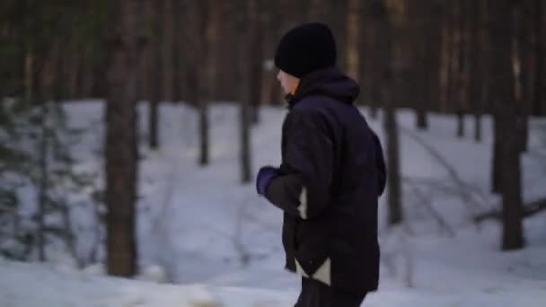 Молодой спортсмен бегает в зимнем лесу — стоковое видео