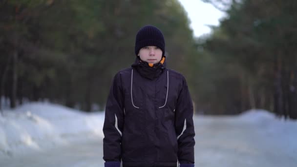 Портрет красивого молодого спортсмена, бегущего трусцой в зимнем лесу — стоковое видео