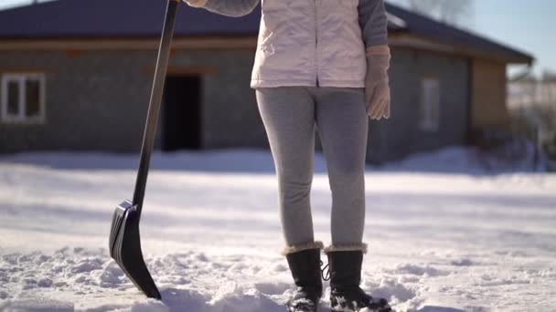 Chica joven se para con una pala en el patio trasero. mujer lista para limpiar la nieve después de la nevada — Vídeo de stock