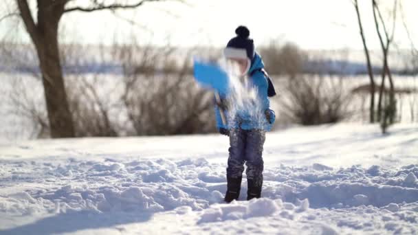 Liten pojke skyfflar snö på vintern — Stockvideo