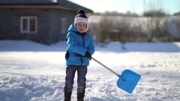 Kleine jongen die sneeuw schept in de winter — Stockvideo