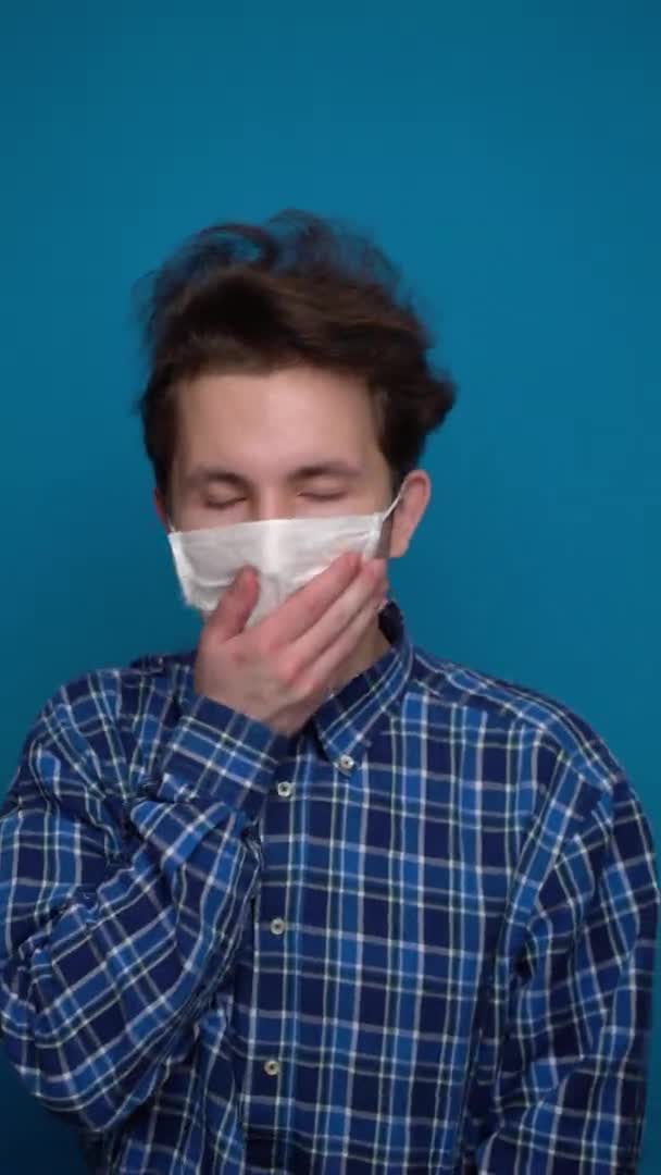 파란 배경에 마스크를 쓴 십 대 청소년 이 기침을 한다 — 비디오
