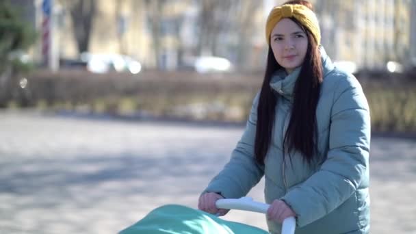 Жінка проходить через парк з коляскою — стокове відео