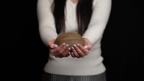 Женщина показывает кокос в руках на черном фоне — стоковое видео