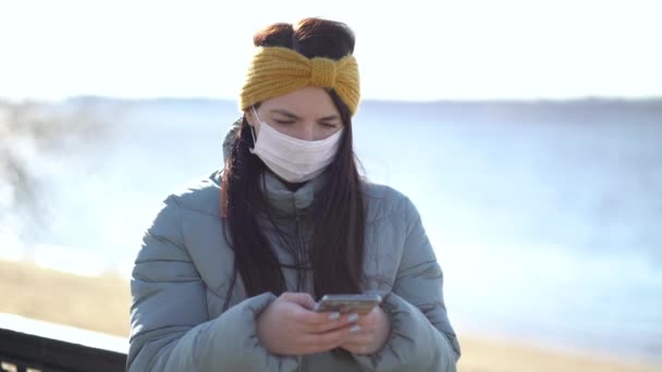 Νεαρή γυναίκα με μάσκα στέλνει μηνύματα στο Smartphone — Αρχείο Βίντεο