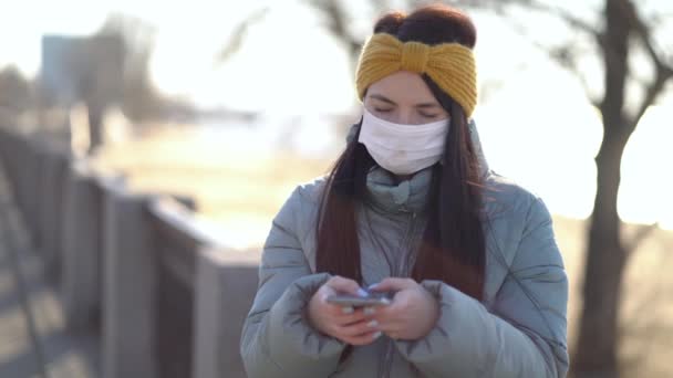 Молода жінка в масці СМС на смартфоні — стокове відео