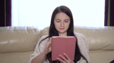 Karantina sırasında evde tıbbi maskeli bir kadın tablet kullanıyor.