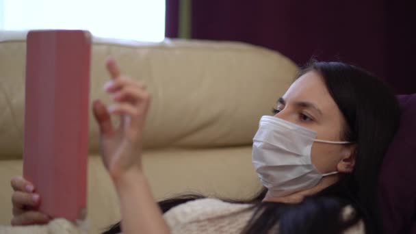 Femme dans un masque médical utilise une tablette à la maison pendant la quarantaine . — Video