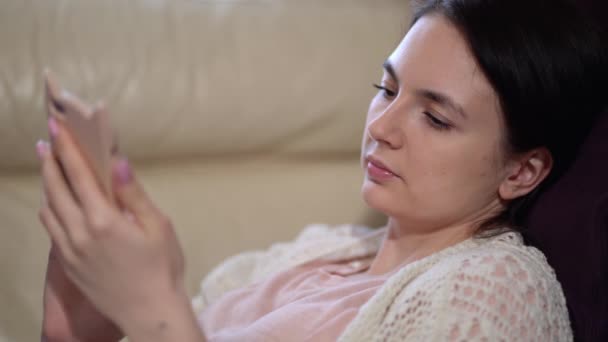 Frau mit medizinischer Maske benutzt während der Quarantäne zu Hause ein Handy — Stockvideo