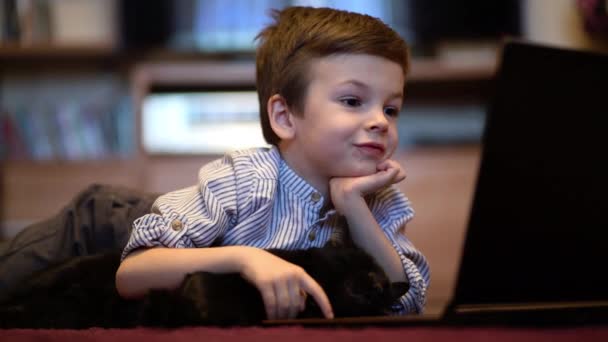 Criança engraçada com gatinho usando um laptop em casa . — Vídeo de Stock