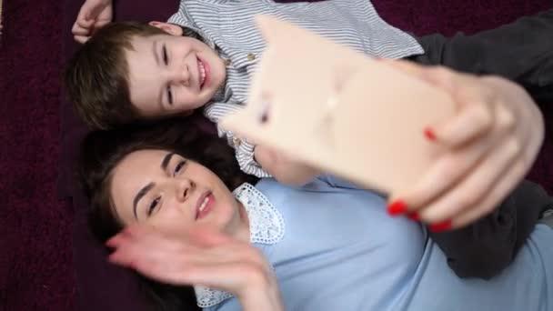 Madre e suo figlio fanno un selfie o una videochiamata al padre o ai parenti sul tappeto . — Video Stock