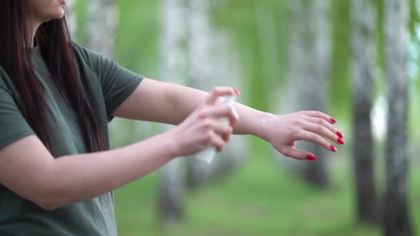 Young woman in a birch grove puts a mosquito repellent on her skin. — Stock Video