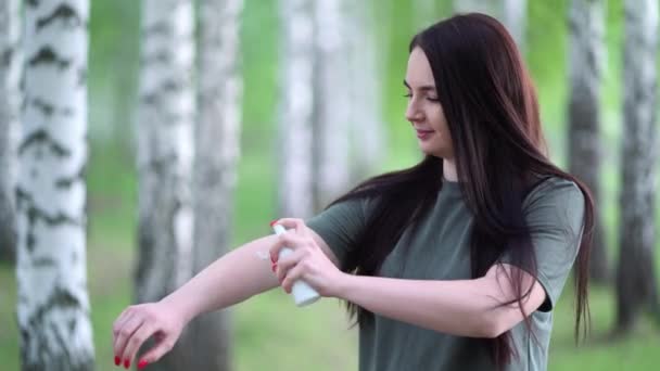 Young woman in a birch grove puts a mosquito repellent on her skin. — Stock Video