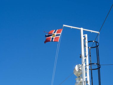Feribot bayrak direğine mavi gökyüzü karşı Norveç posta bayrağı