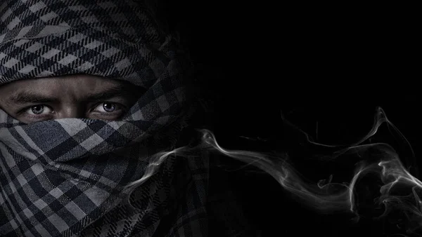 muslim in camouflage mask on a black smoke background