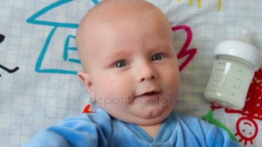 Bebek yatağında döşeme ve biberon yemek yiyor. Kaybetme ve almak çalışıyorum. Gülümseyen ve çığlık