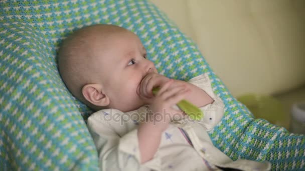 Baby zit op de stoel van de kinderen. Moeder voedt het kind met lepel voor de eerste keer. Close-up — Stockvideo