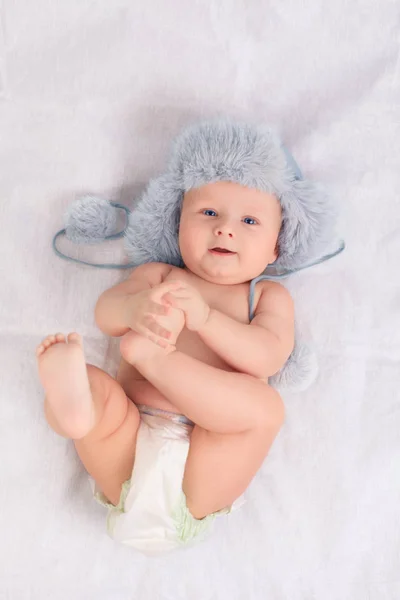Lindo bebé de nueve meses yace boca arriba y sostiene su pierna en sus manos —  Fotos de Stock
