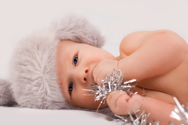 Um bebê bonito de nove meses em chapéu peludo que coloca em um fundo branco Fotografia De Stock