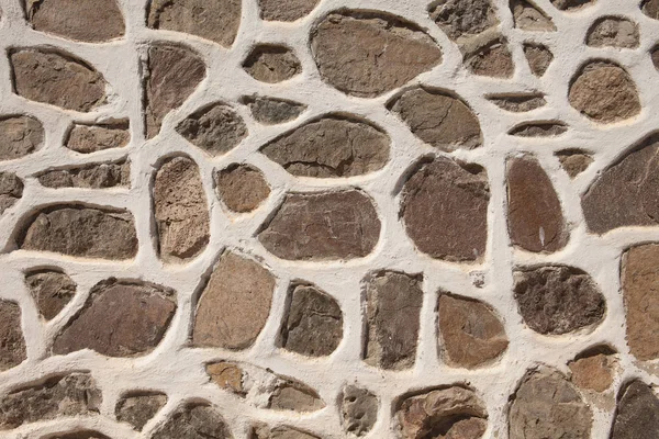 Fondo de pared de piedra hecha de rocas planas grises y marrones pálidos con masilla blanca entre ellas — Foto de Stock