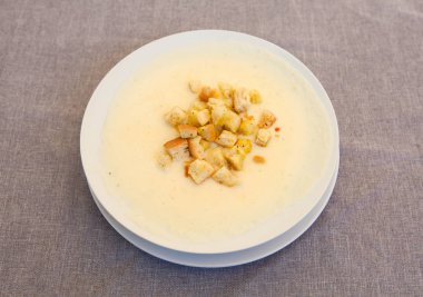 Lezzetli krem çorbası tost beyaz plaka ve keten gri arka plan üzerinde bir kafe üst görünümünde görev yaptı.