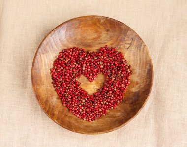 Sevgililer günü kavramı tebrik'ın kartı arka plan şablonu. Kalp ortasında bir kalp ile dokulu ahşap plaka üzerinde pembe biber avuç şeklinde