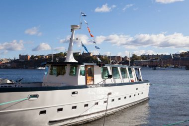 Stockholm, İsveç - 04 Ekim 2016: Küçük beyaz seyahat tekne şehir merkezi İsveç tarihi binalar ile kanalda farklı yelken bayrak ile arka planda