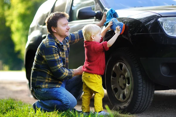 Батько зі своїм маленьким сином миє машину разом — стокове фото