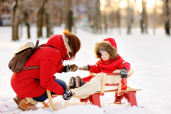 美しい幼児の少年と彼の母親は、雪の降る公園で楽しんでの肖像画 — ストック写真