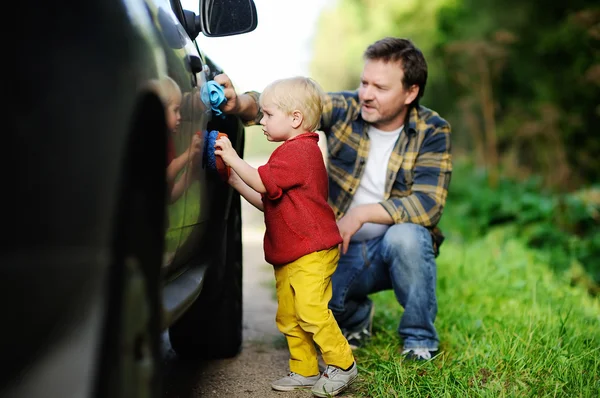 Father with his toddler son washing car together