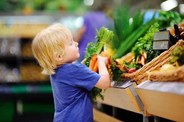 Schattig peuter jongen in supermarkt kiezen verse biologische wortelen — Stockfoto