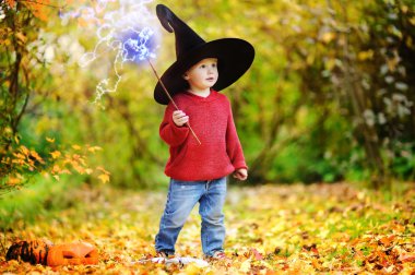 Sivri şapkalı açık havada sihirli değnek ile oynarken yürümeye başlayan çocuk