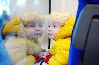 Tren pencere dışında hareket ederken bakarak şirin yürümeye başlayan çocuk