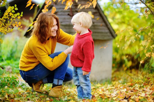 Menino bonito e sua jovem mãe no outono — Fotografia de Stock