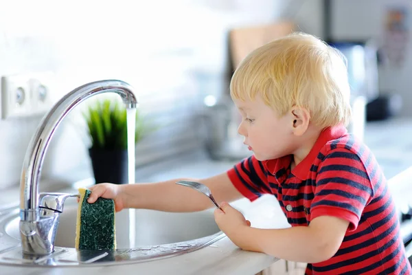 Lindo niño lavando platos en la cocina doméstica —  Fotos de Stock