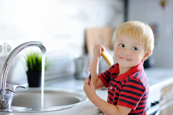 Anak laki-laki lucu mencuci piring di dapur domestik — Stok Foto