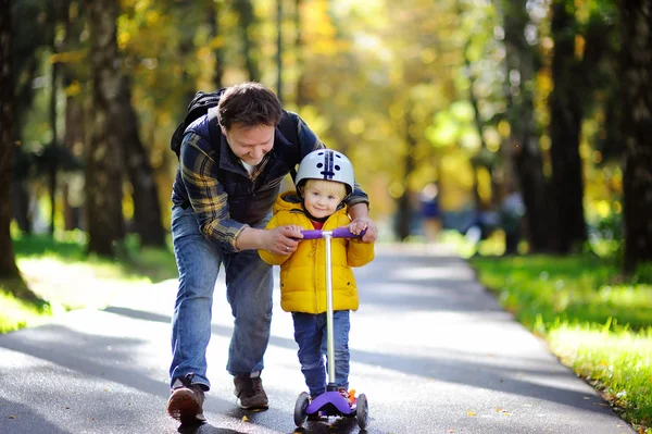 Otec, ukazující jeho syn batole, jak jezdit na koloběžce — Stock fotografie