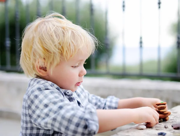 Симпатична блондинка маленький хлопчик грає з маленькими каменями на відкритому повітрі — стокове фото
