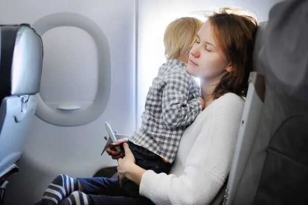 Mujer joven viajando con su pequeño hijo en un avión — Foto de Stock