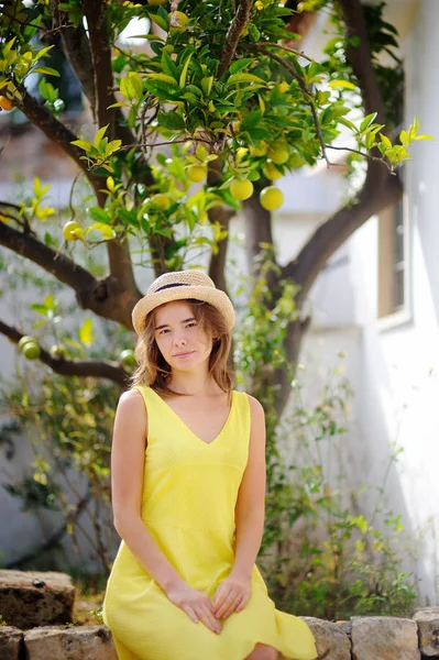 Young beautiful girl picking fresh ripe limes or lemons in sunny garden in Italy — Stock Photo, Image