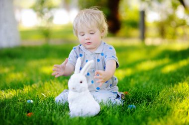 Paskalya günü bahar bahçesinde Paskalya yumurtası arayan küçük bir çocuk.