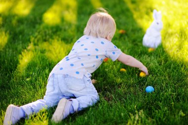 Paskalya günü bahar bahçesinde Paskalya yumurtası arayan küçük bir çocuk.